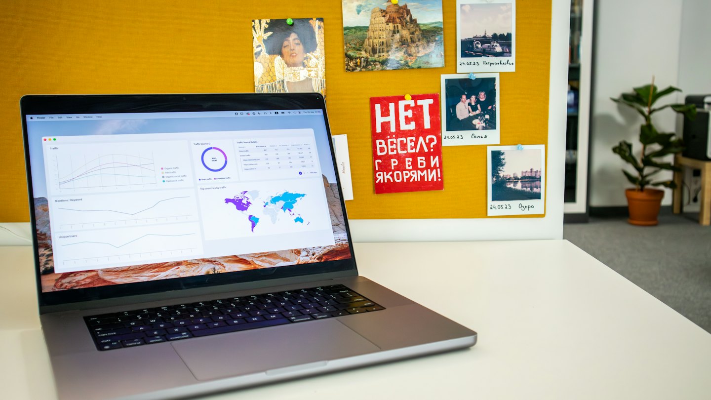 Laptop showing data analytics dashboard on a white desk.